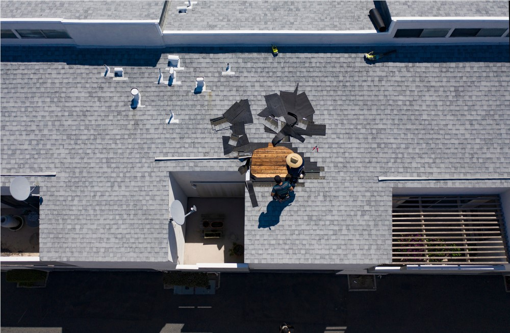 Roofer performing a targeted roof repair on damaged shingles and flashing