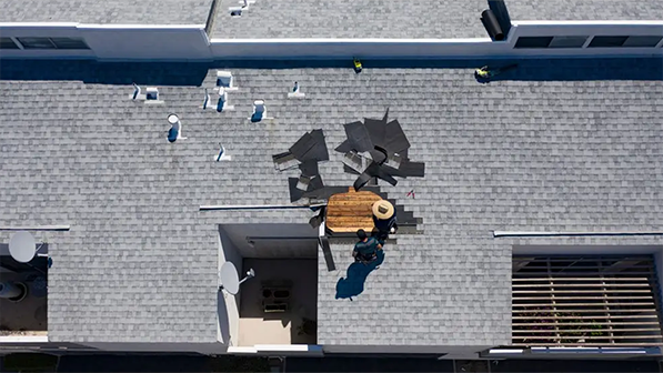 Roofer performing a targeted roof repair on damaged shingles and flashing